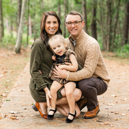 Two parents and their daughter outside, smiling