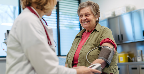 Doctor putting blood pressure cuff on older patient